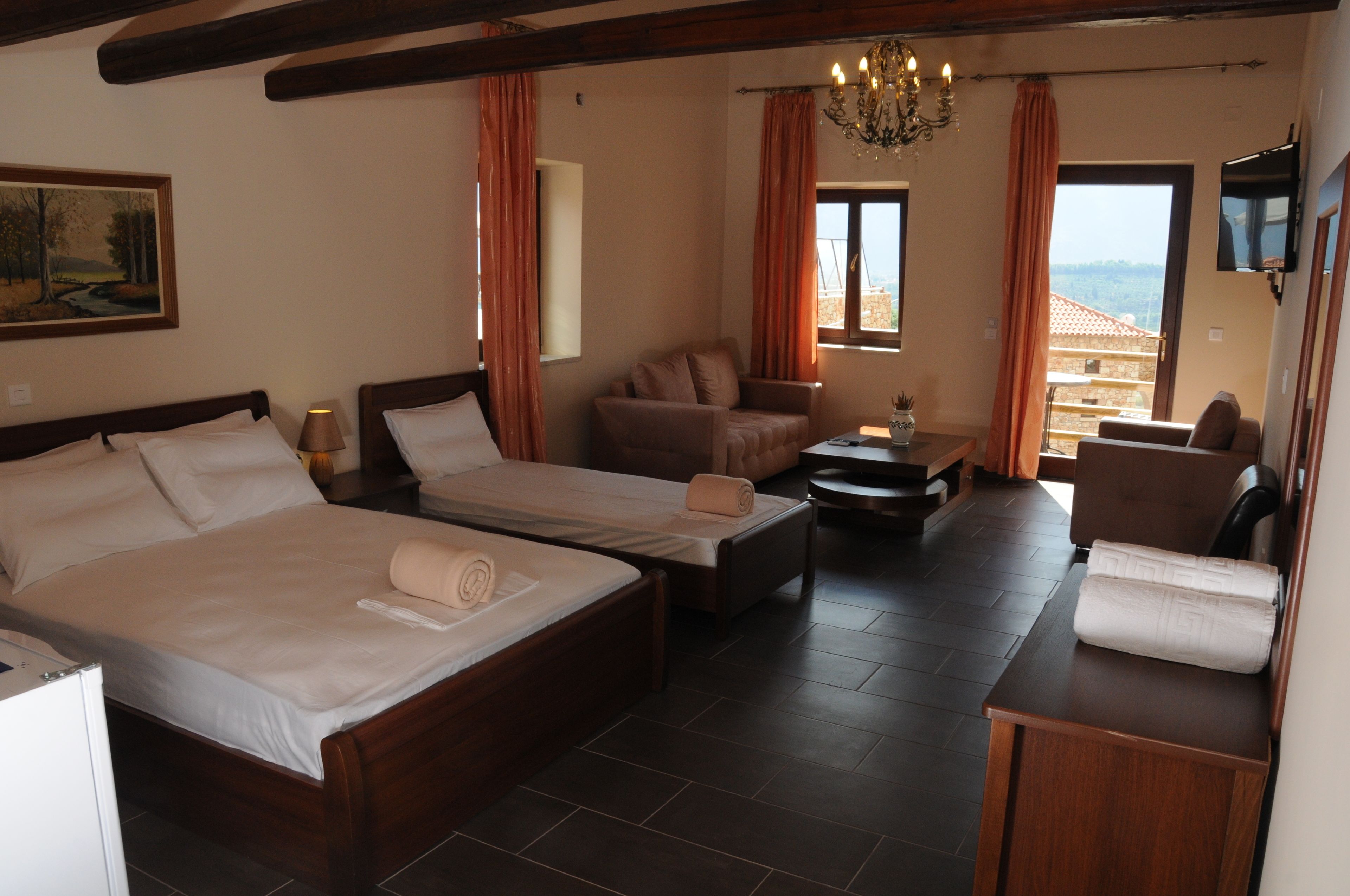 A hotel room with two beds, a sofa, a small table, and a TV.