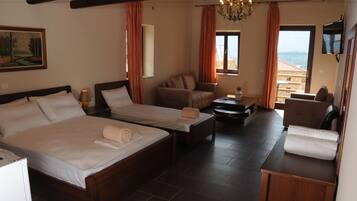 A hotel room with two beds, a sofa, a small table, and a TV.