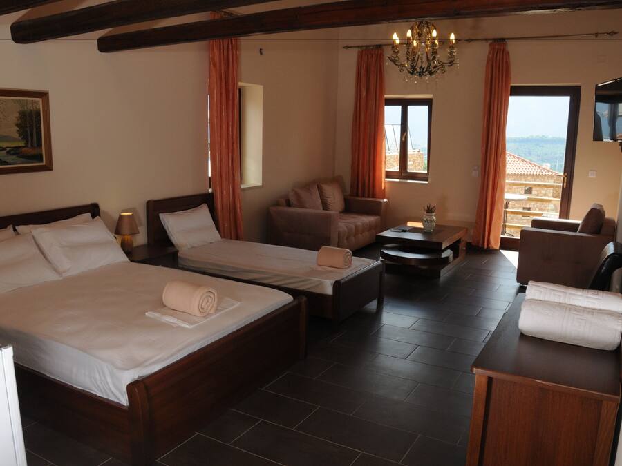 A hotel room with two beds, a sofa, a small table, and a TV.