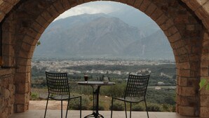 Un espacio al aire libre con una mesa y dos sillas, con vistas a un paisaje montañoso.