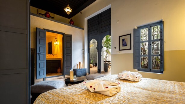 Un dormitorio con cama, mesita de noche, ventana con vistas y puerta que da a un balcón.