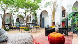 Un espacio al aire libre con mesas y sillas, rodeado de arcos y plantas.