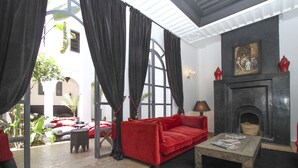 Una habitación con un sofá rojo, una mesa baja de piedra y una chimenea.