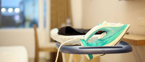 A hotel room with a bed, a chair, and an ironing board with an iron.