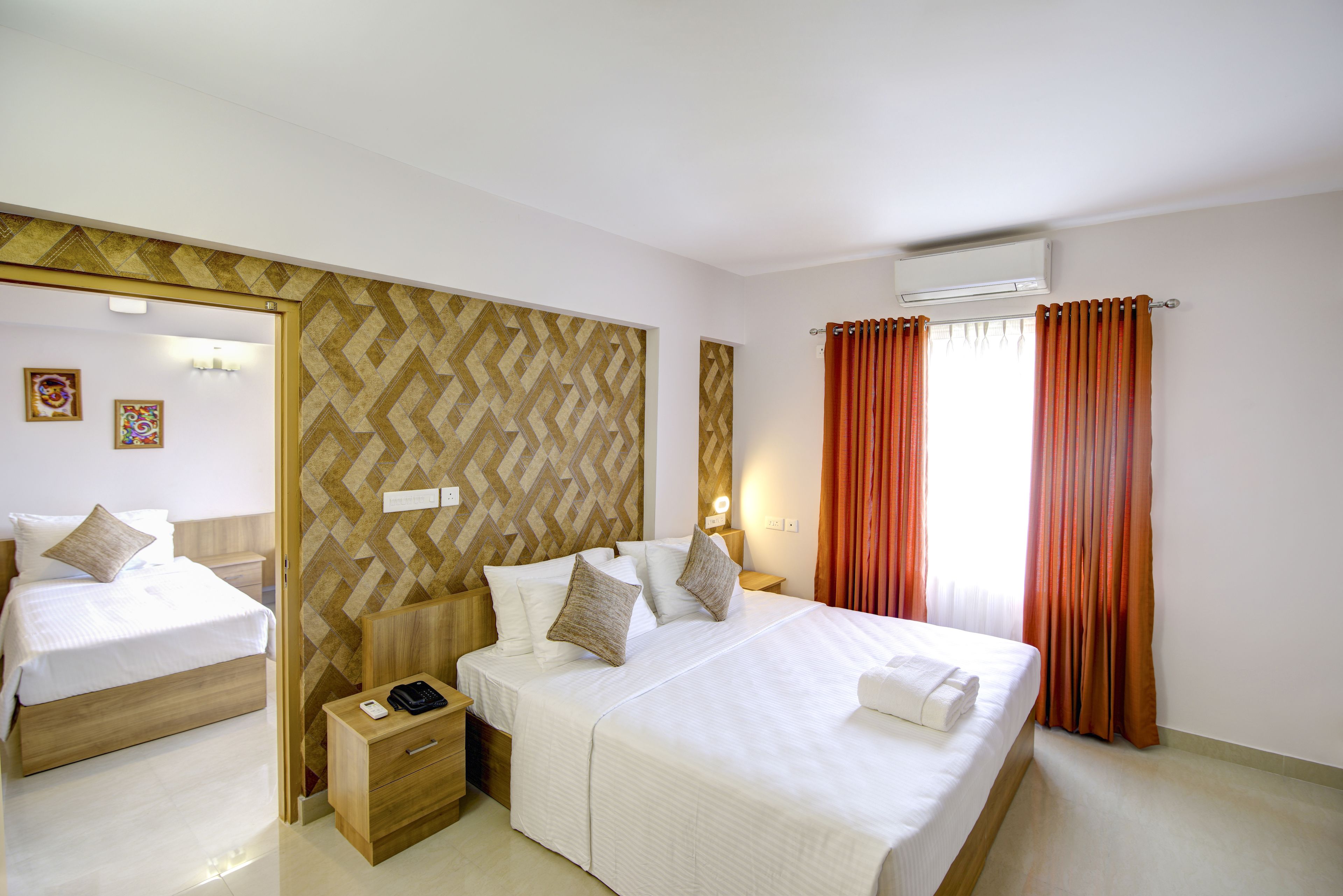 Une chambre d’hôtel avec un grand lit, une table de chevet avec un téléphone, un miroir et une fenêtre avec des rideaux.