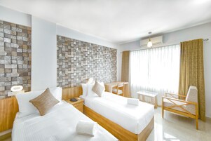 Habitación de hotel con dos camas, un escritorio, una silla y una pared con diseño de piedra.