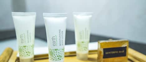 Three tubes of body lotion and a bar of soap on a wooden tray.