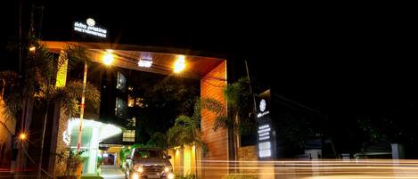 Un edificio con un letrero que dice "idno pristine" y un coche circulando por la entrada.
