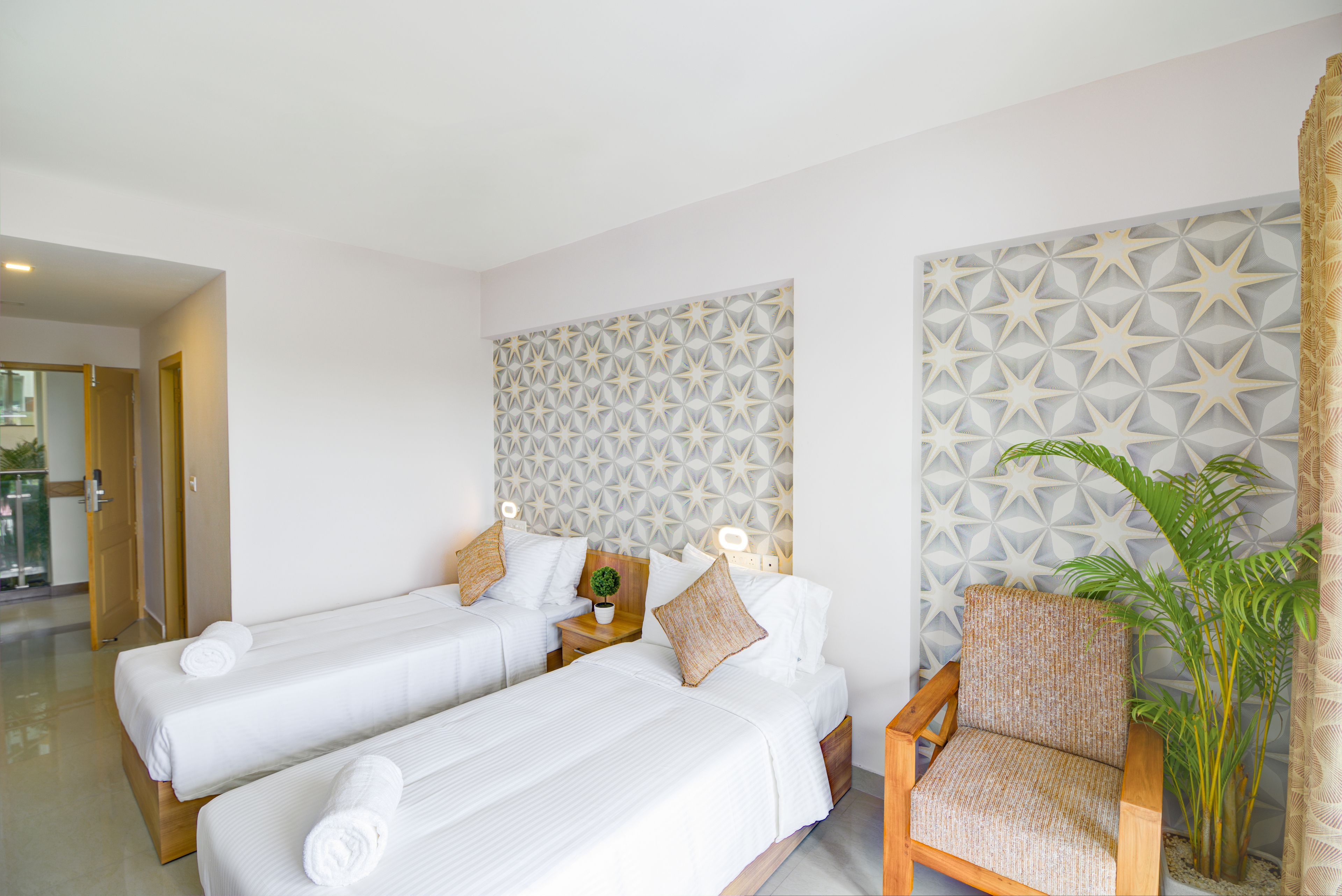 A hotel room with two single beds, a wooden nightstand, a chair, and a decorative wall panel.