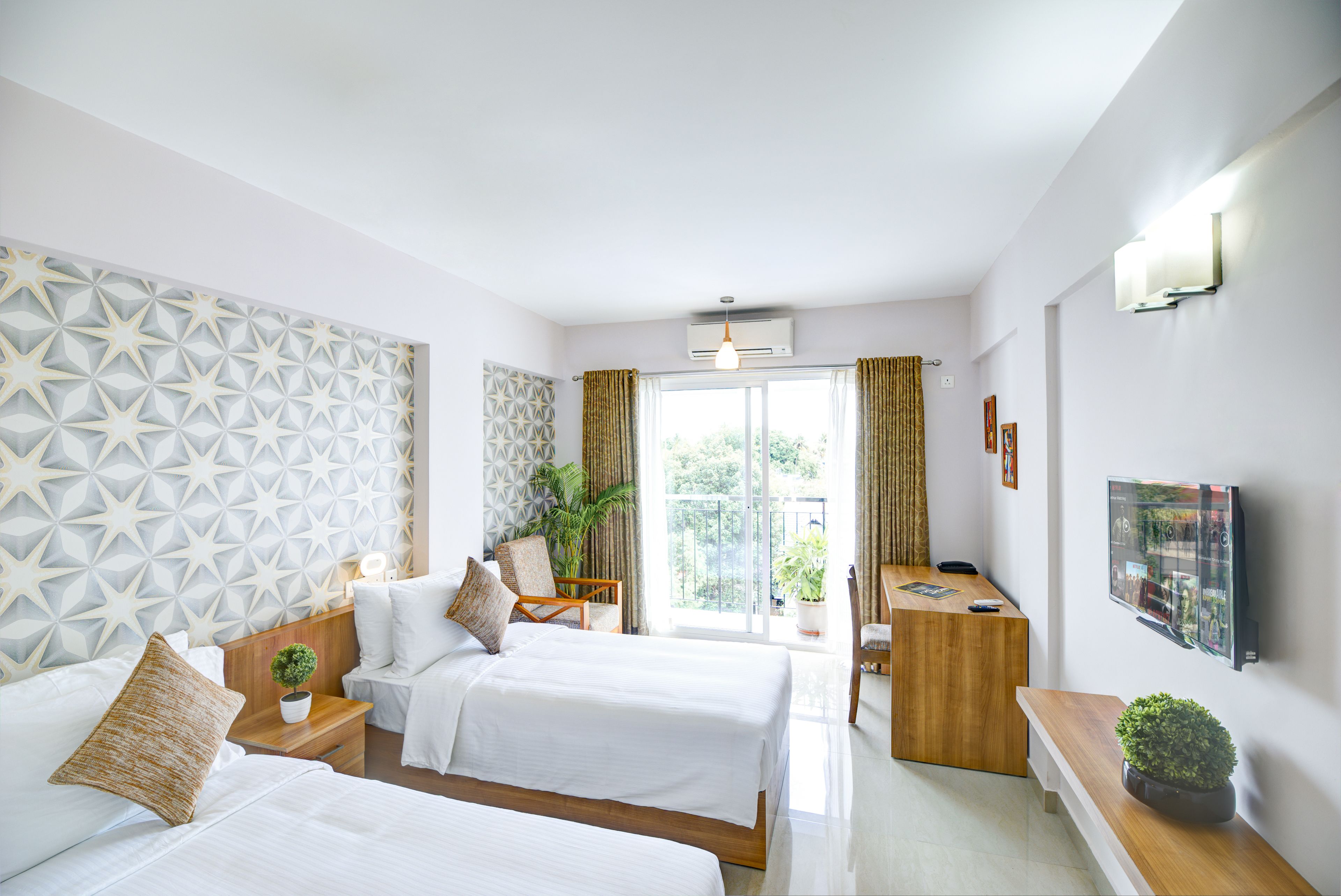 Une chambre d’hôtel avec deux lits, un bureau, une chaise, une télévision et un balcon avec des rideaux.
