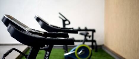 Un gimnasio con bicicletas estáticas y una cinta de correr.