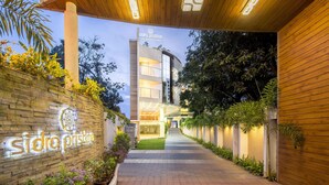 A modern building with a sign reading "sidro pristine" and a pathway lined with plants. - Sidra Pristine Hotel & Portico Halls (Kanayannur)
