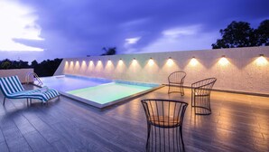 A rooftop pool area with a wooden deck, two lounge chairs, and a table with wire chairs. - Sidra Pristine Hotel & Portico Halls (Kanayannur)