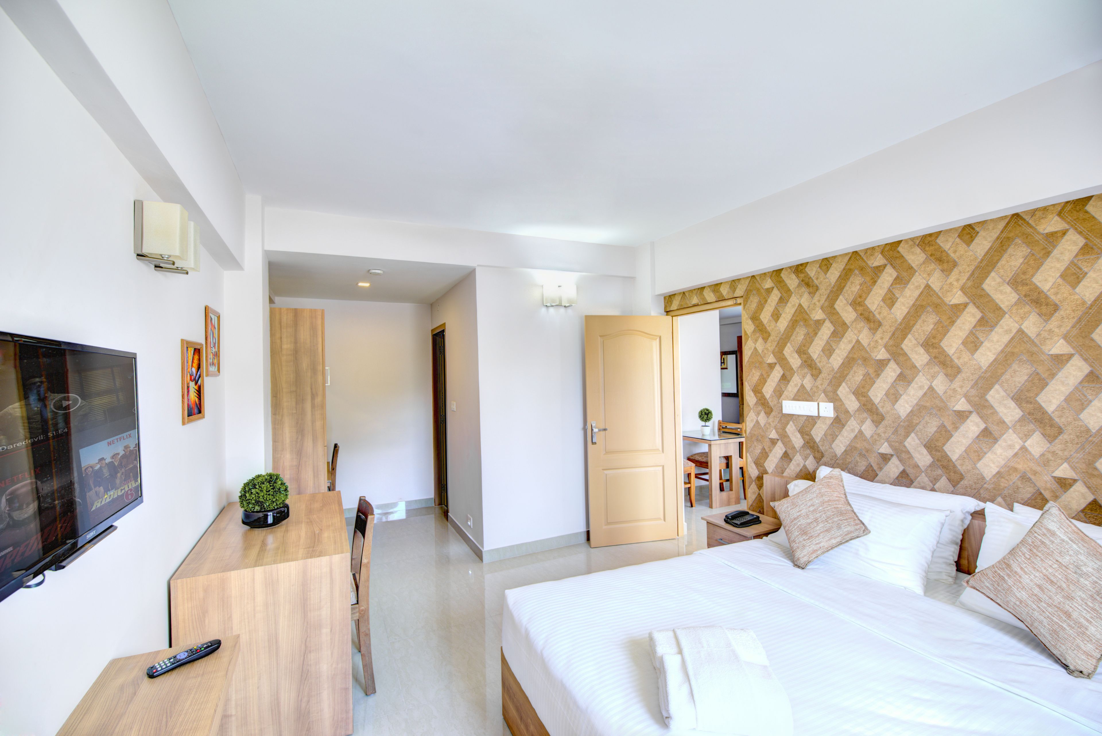 A hotel room with a bed, a desk, a television, and a door leading to a bathroom.