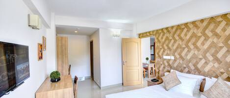A hotel room with a bed, a desk, a television, and a door leading to a bathroom.
