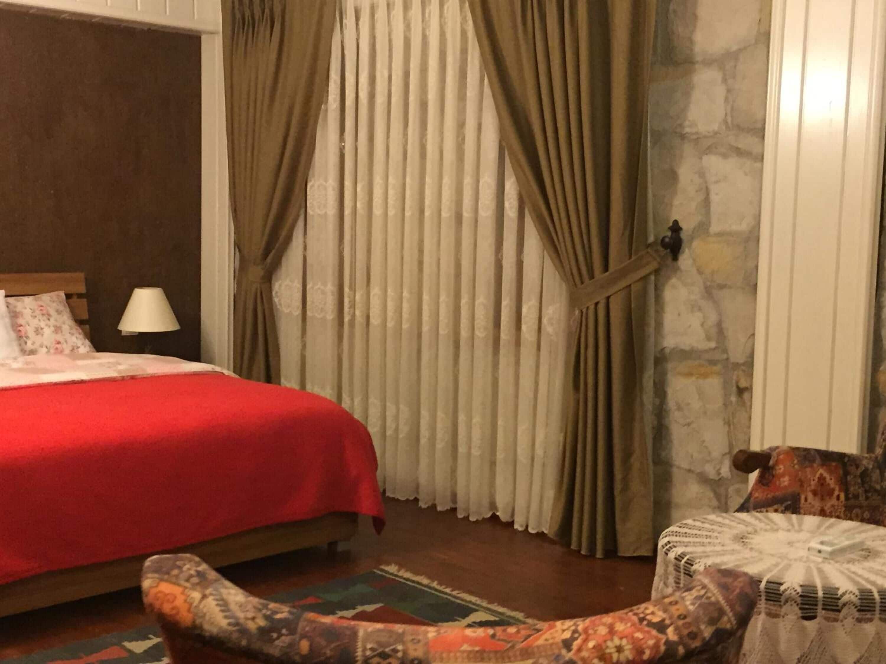 Une chambre à coucher avec un lit, des rideaux, une lampe et un tapis à motifs.