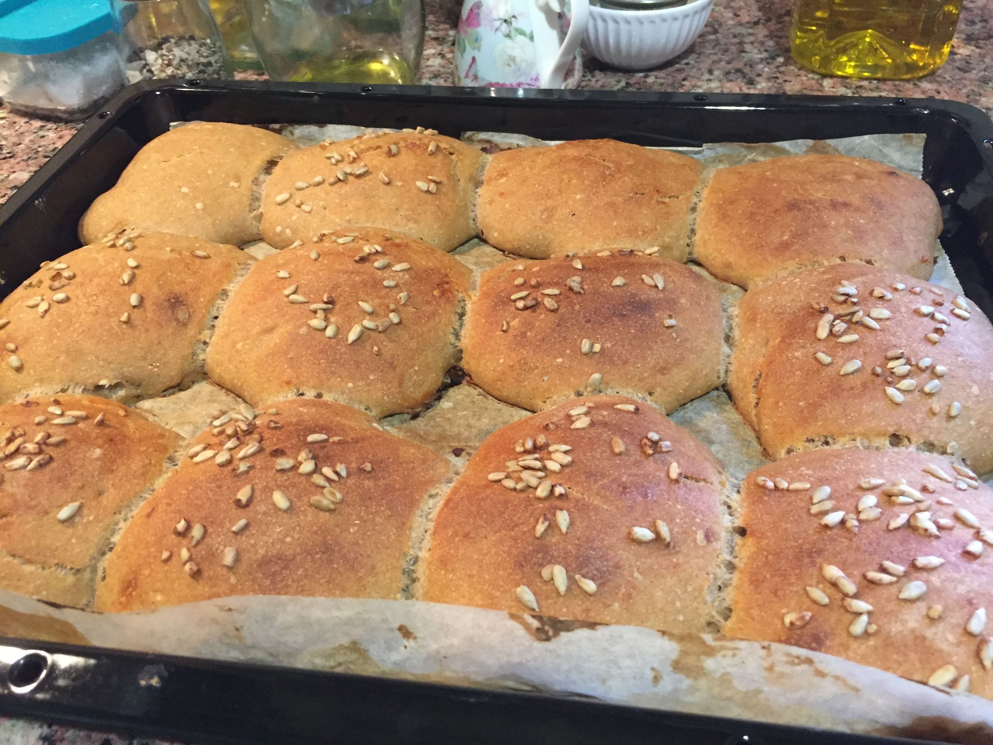Une assiette de petits pains fraîchement cuits, saupoudrés de graines de sésame, posée sur un plan de travail de cuisine.