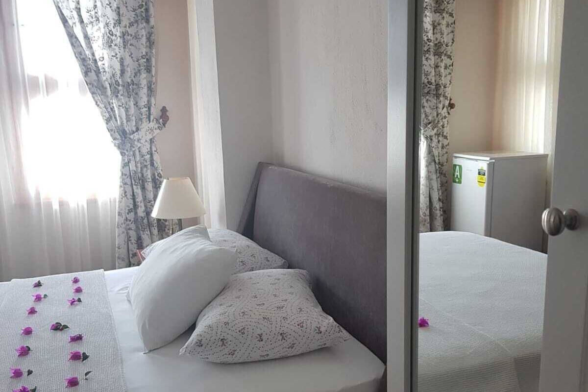 A hotel room with a bed, a nightstand, a lamp, and a mirror.