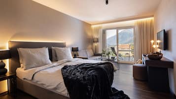 Una habitación de hotel moderna con una cama grande, un sofá, un escritorio y un balcón con vista a la montaña.