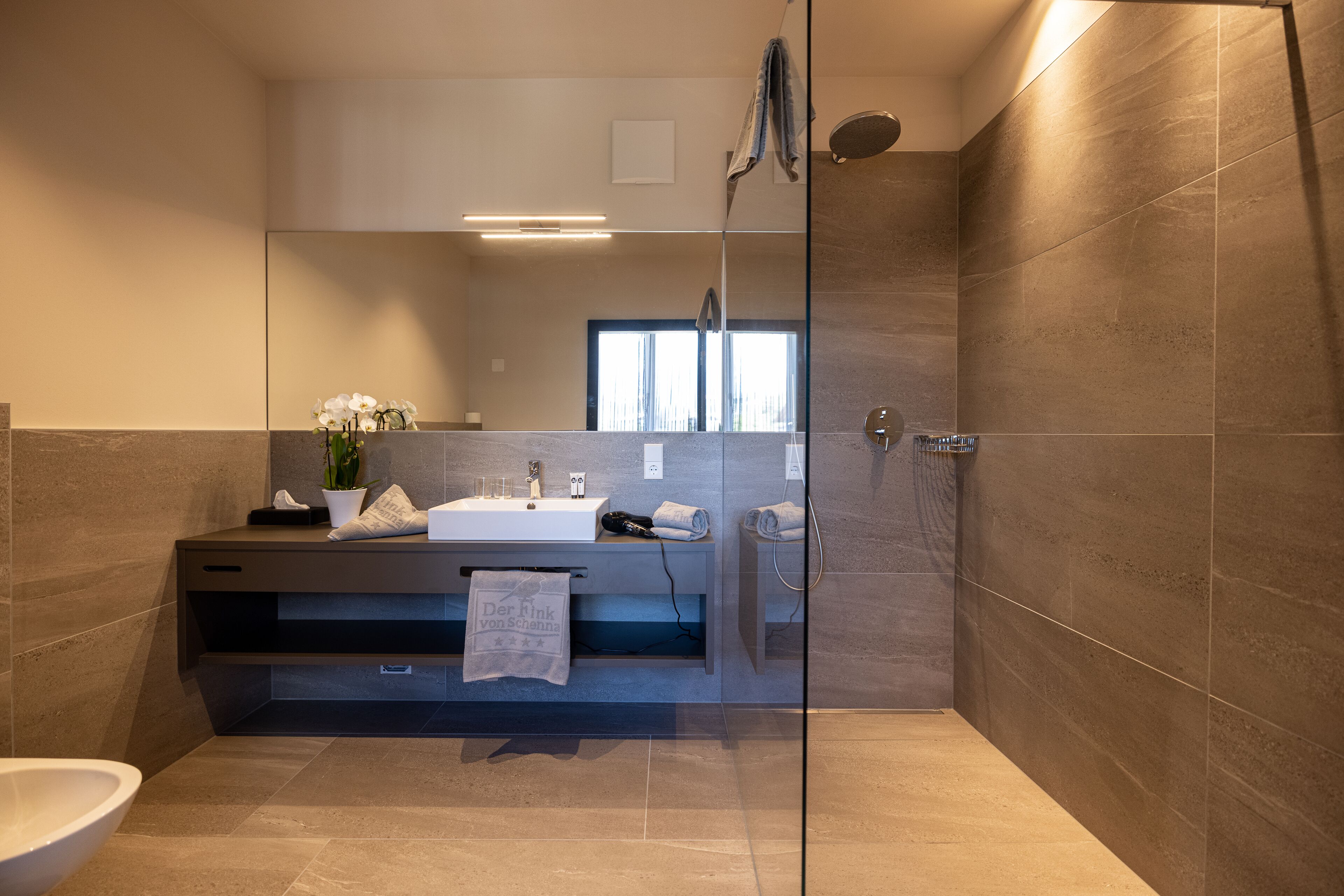 Un baño moderno con cabina de ducha de vidrio, un lavamanos y un inodoro.