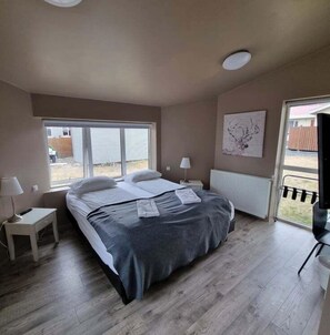 Een slaapkamer met een bed, nachtkastjes, een radiator en een raam.