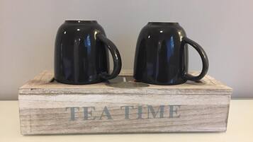 Two black mugs on a wooden tray with the words "TEA TIME" engraved on it.