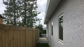 Une maison entourée d’une clôture en bois, avec un chemin de gravier et une pelouse.