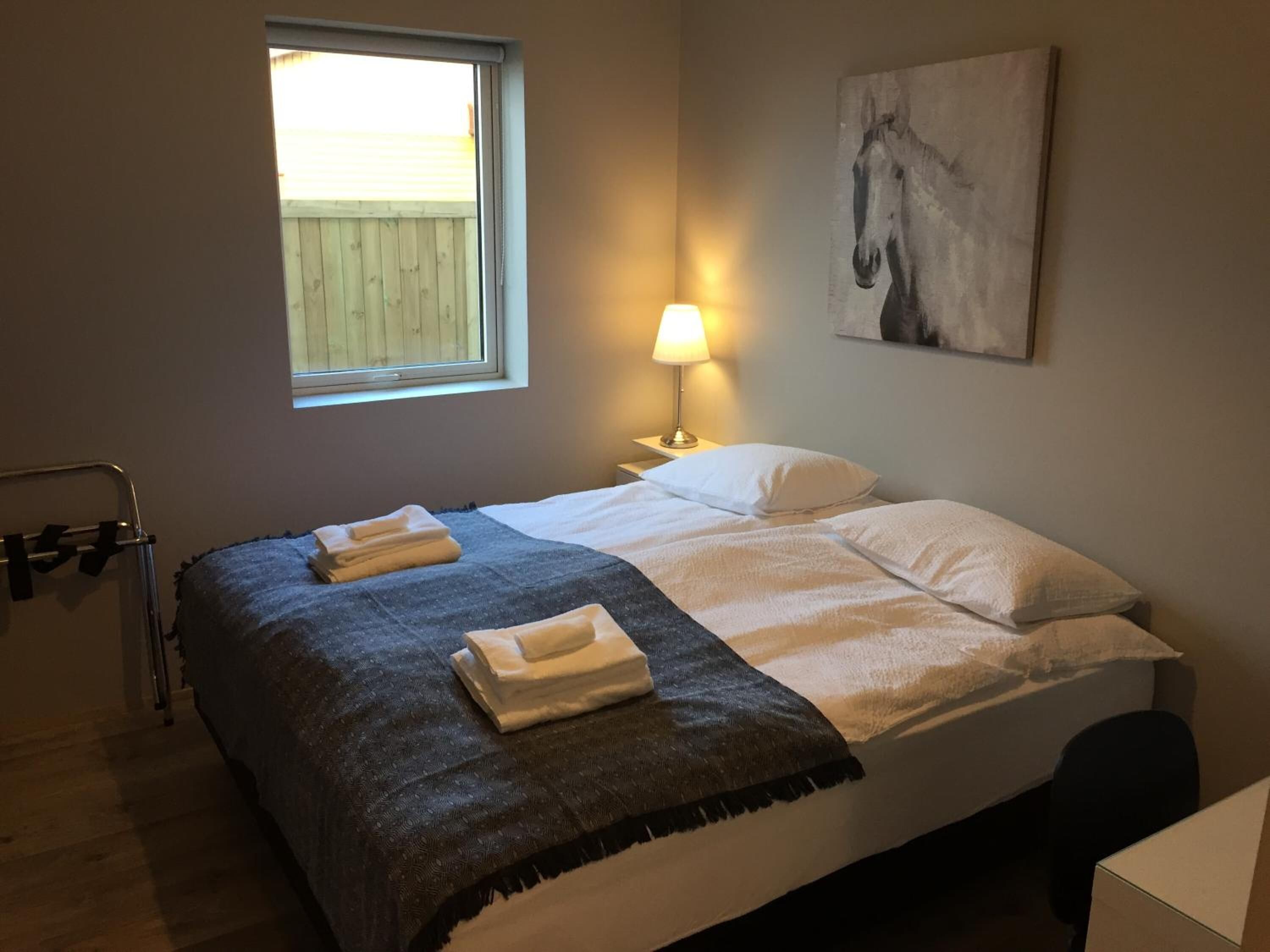 Une chambre à coucher avec un lit, une fenêtre, une lampe et un tableau au mur.