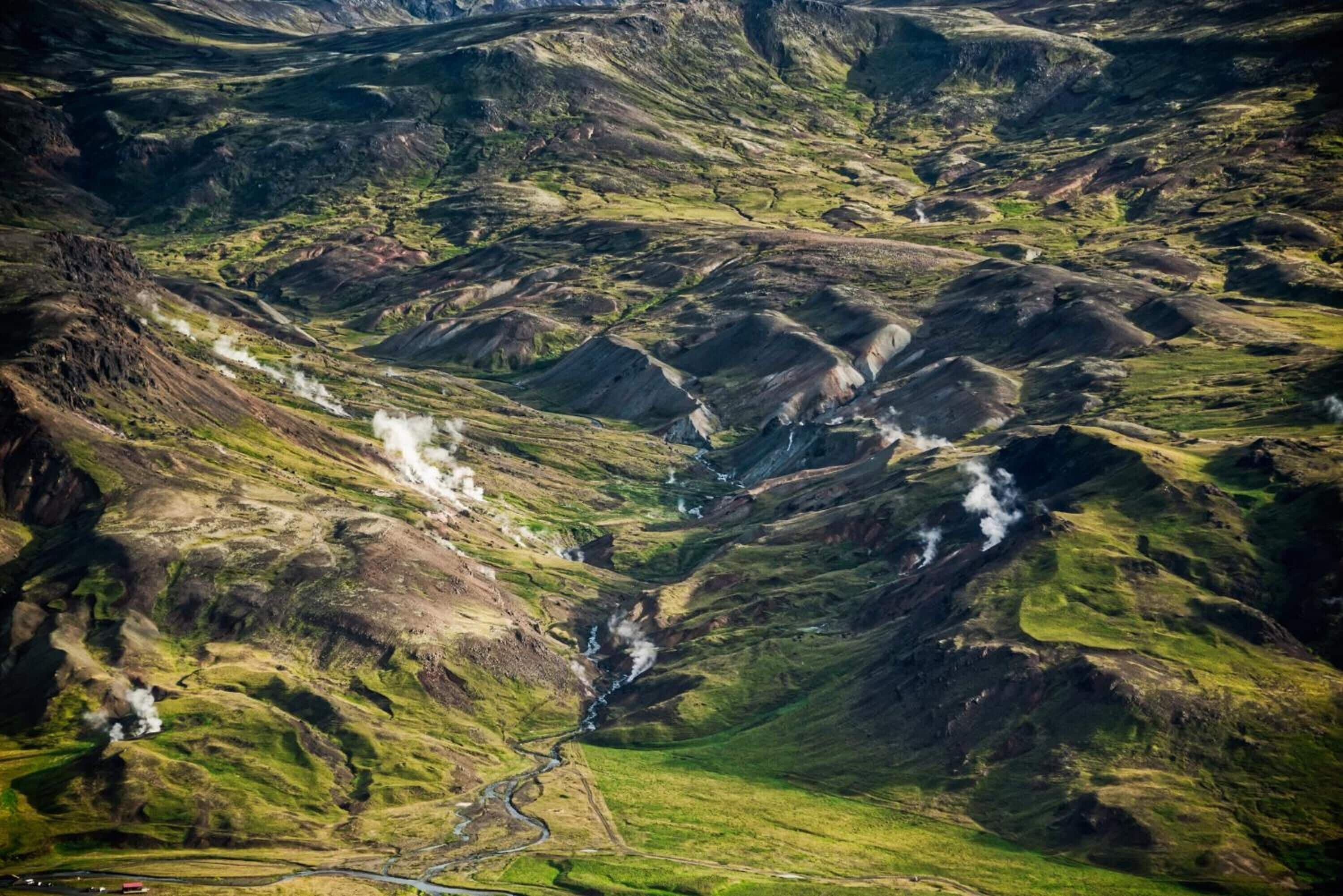 A mountainous landscape with a winding road and a visible stream.