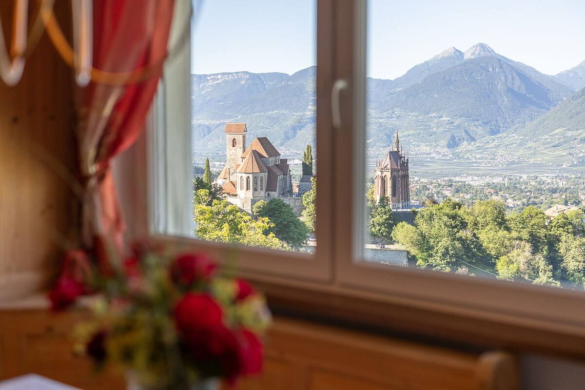 A view of a mountain landscape with two prominent churches through a window.