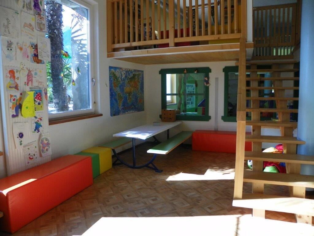 Een kinderspeelkamer met een videbed, een klein tafeltje en kleurrijke zithoeken.