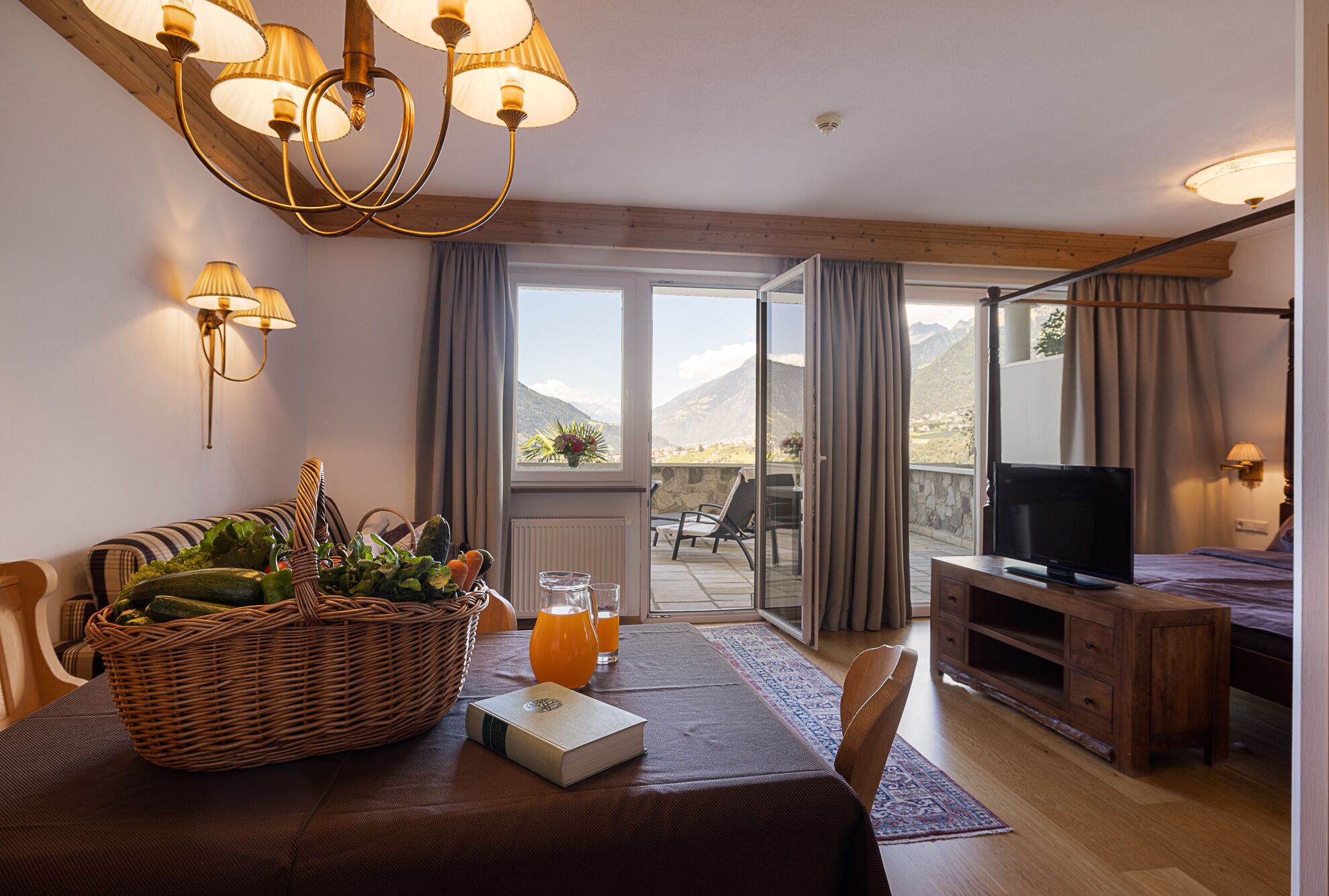 Une chambre d’hôtel dotée d’un coin repas, d’une télévision et d’un balcon offrant une vue sur la montagne.