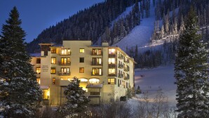 Et hotel med flere etager og altaner, beliggende i et snækkedækket bjerglandskab.