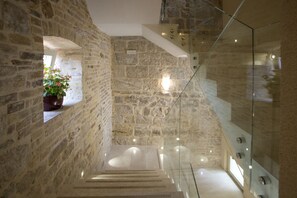 A stone-walled staircase with a glass railing, leading to a higher floor. - Aspalathos Residence (Split)
