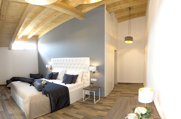 A bedroom with a large bed, a small bedside table, and a hanging light fixture.