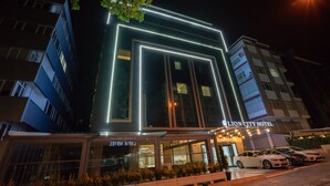 Het uiterlijk van het Lion City Hotel met verlichte neonborden die de structuur van het gebouw omlijnen.