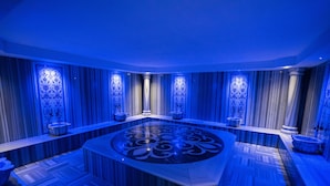 Een luxe badkamer met een centraal rond badkamermeubel, gedetailleerde wandpanelen en een gestreept vloerpatroon.