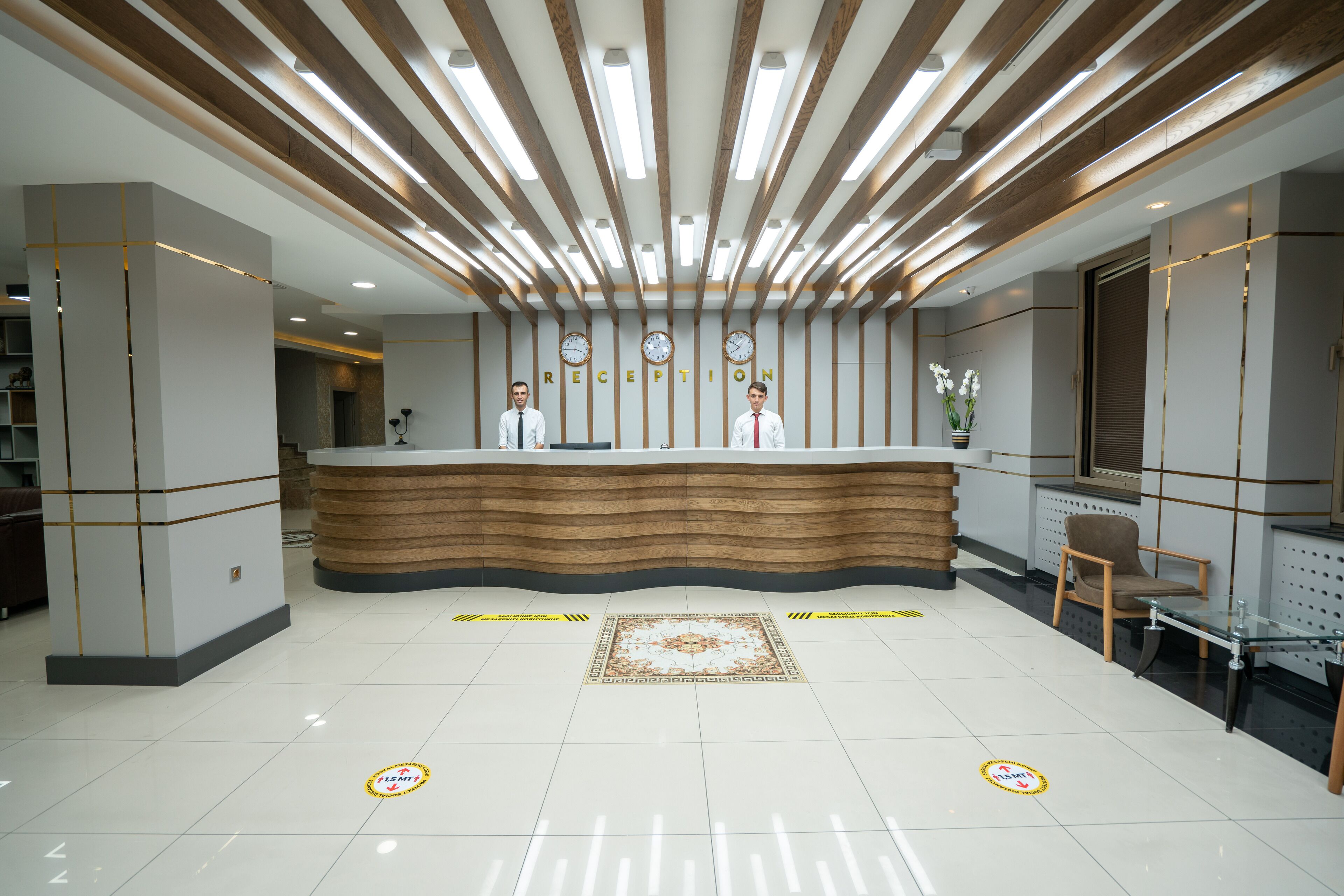 A reception area with a wooden reception desk, two receptionists, and a decorative rug.