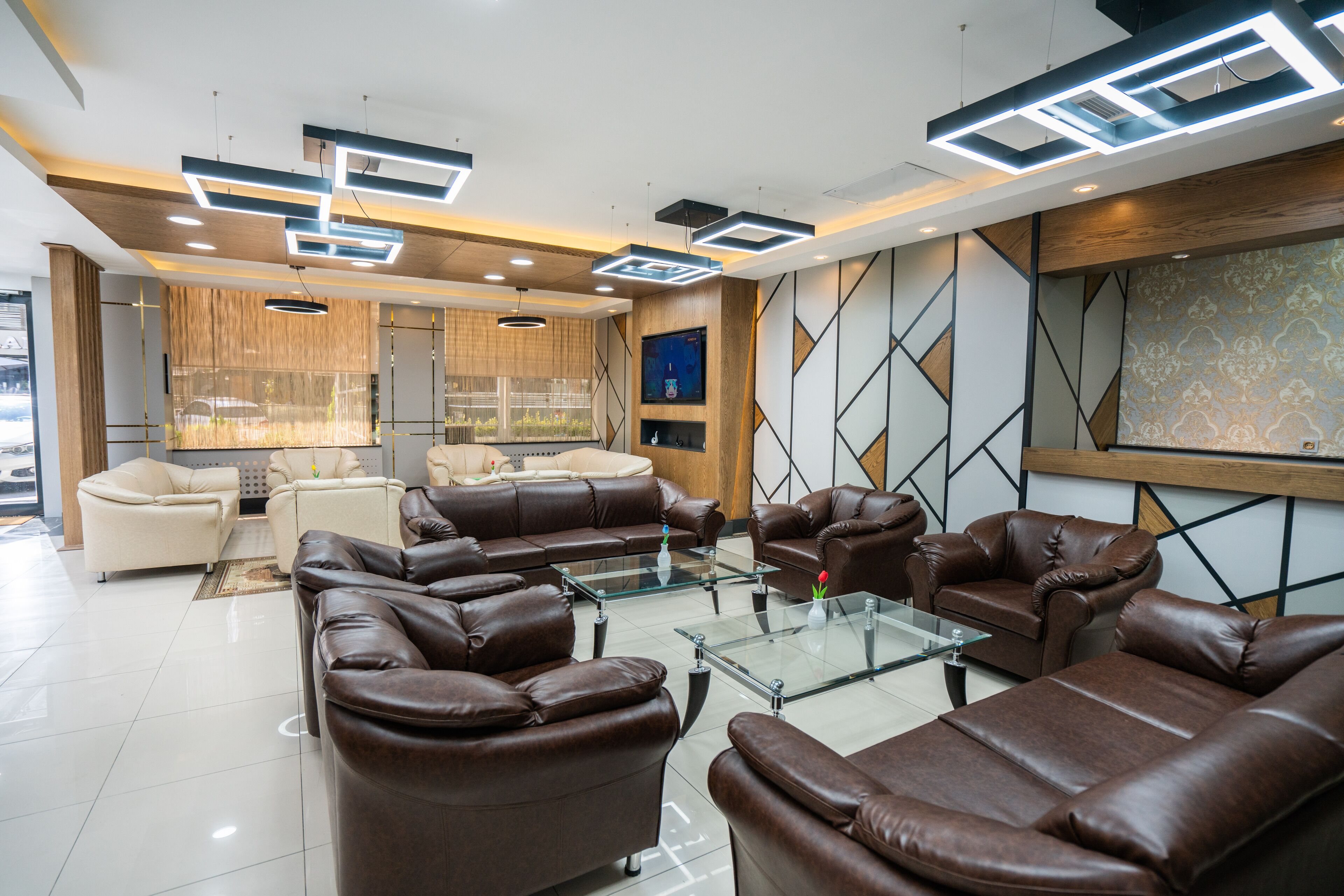 Una sala de estar moderna con sofás de cuero, una mesa de centro de vidrio y una gran pantalla de televisión.