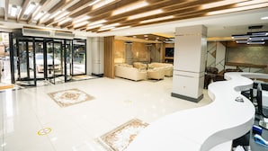 Een moderne hotel lobby met een receptiebalie, zithoek en glazen ingang.