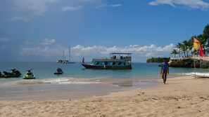 Gần bãi biển, cát trắng, ghế dài tắm nắng, dù trên bãi biển 