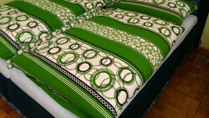 A bed with green and white patterned bedding, a wooden nightstand, and a dark headboard. - Large Apartment in the heart of Slovácko (Kunovice)