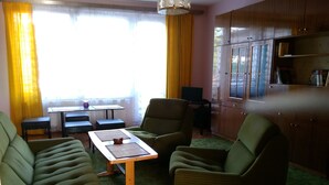 A living room with green upholstered chairs, a wooden coffee table, and a television on a stand. - Large Apartment in the heart of Slovácko (Kunovice)