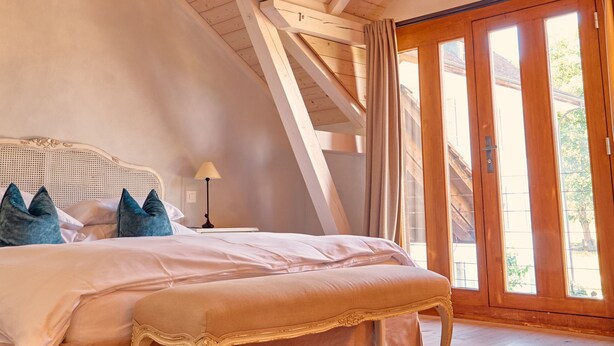 A bedroom with a large bed, wooden beams, a window, and a door. - Chateau Salavaux (Vully-les-Lacs)