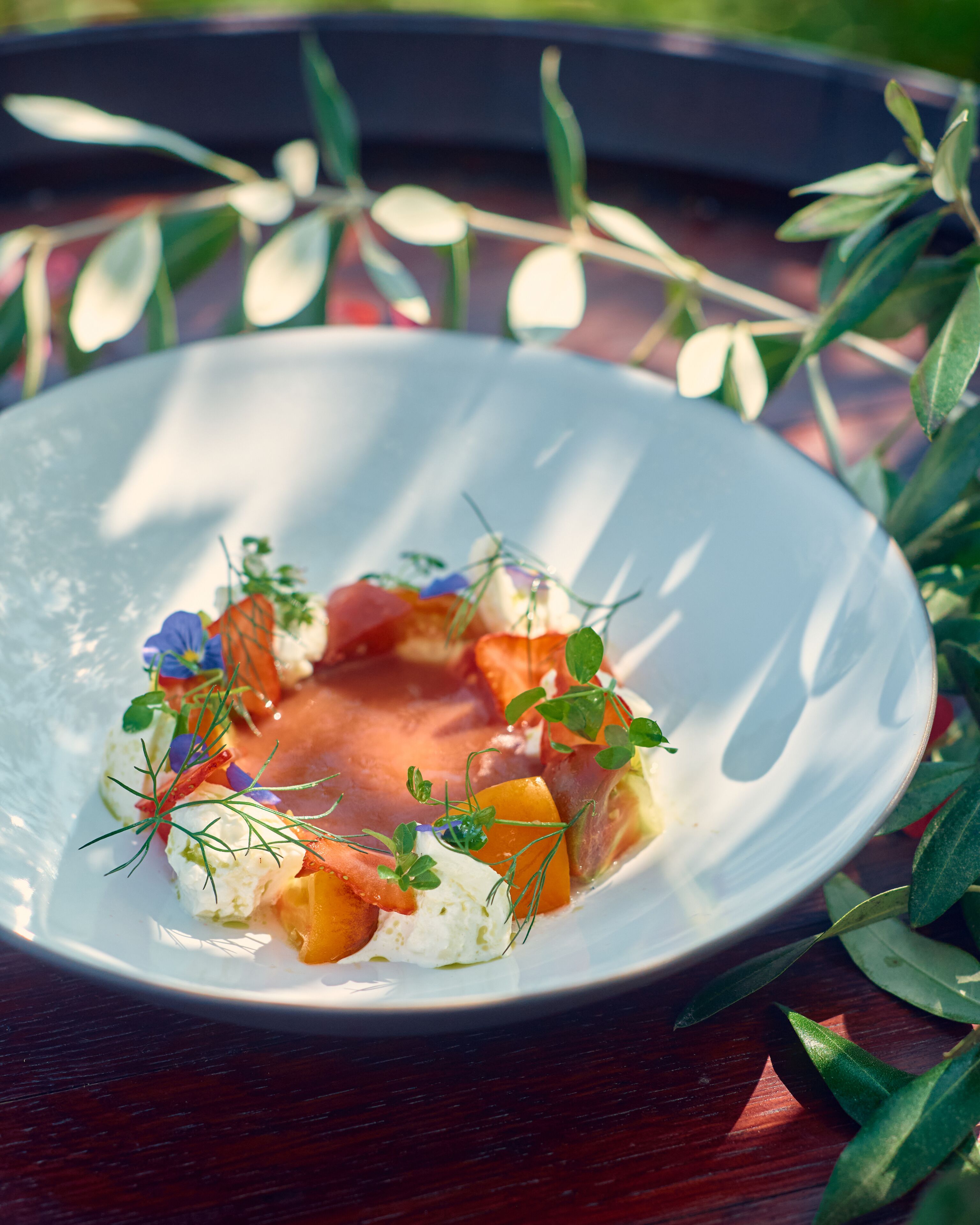 A white plate with a colorful salad on a wooden table.