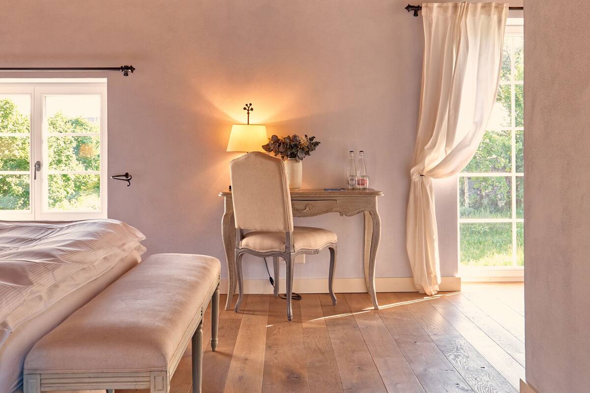 Een slaapkamer met houten plafond, een bed, een bureau met stoel en een raam met gordijnen.