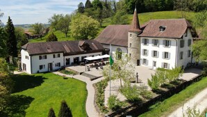 A large white building with a stone tower, multiple windows, and a sloped roof. - Chateau Salavaux (Vully-les-Lacs)