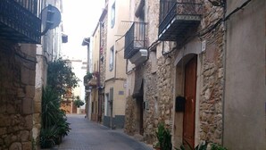 A narrow street with stone buildings, some with balconies and satellite dishes. - Hotel La Cava (Cabanes)