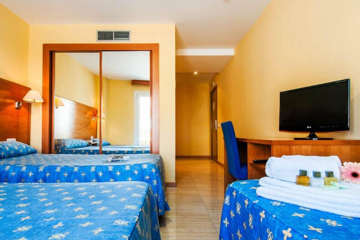 Una habitación de hotel con dos camas, televisión, escritorio y una silla.
