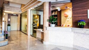 A modern hotel lobby with a reception desk, a staircase, and a glass door leading to another area. - Hotel La Cava (Cabanes)